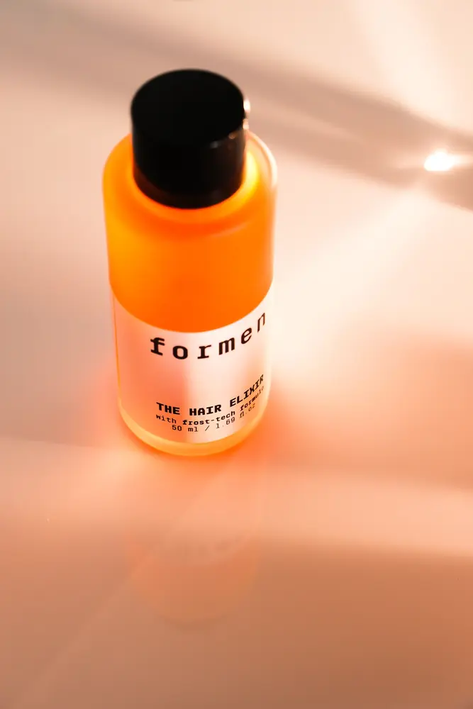 Botol The Hair Elixir dalam pencahayaan hangat